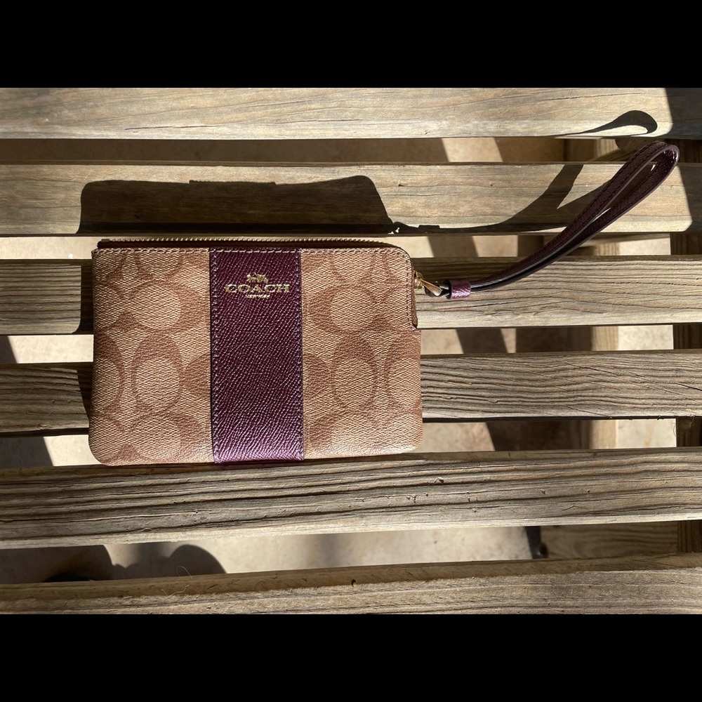 Small Coach wristlet with Coach logo and purple details.